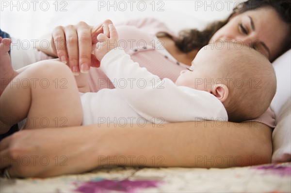 Mother and baby boy (2-5 months) lying together on bed. Photo: Jamie Grill
