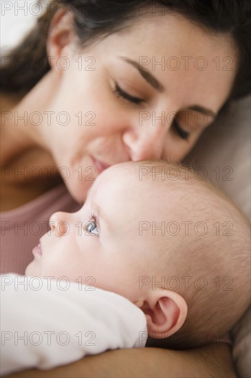 Mother and baby boy (2-5 months) lying together on bed. Photo : Jamie Grill