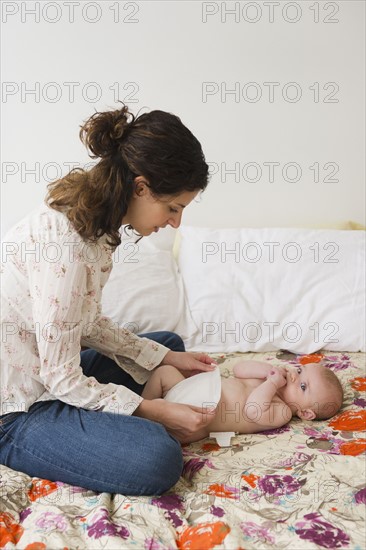 Mother changing baby boy (2-5 months) . Photo : Jamie Grill