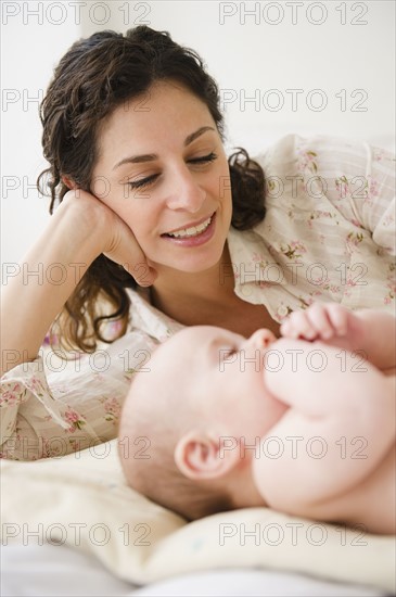 Mother and baby boy (2-5 months) plying together on bed. Photo : Jamie Grill