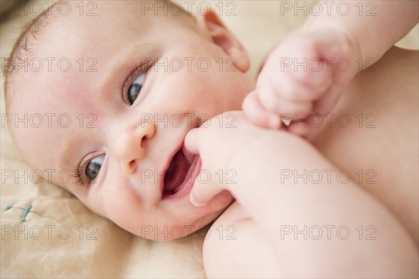 Baby boy (2-5 months) lying on bed. Photo : Jamie Grill