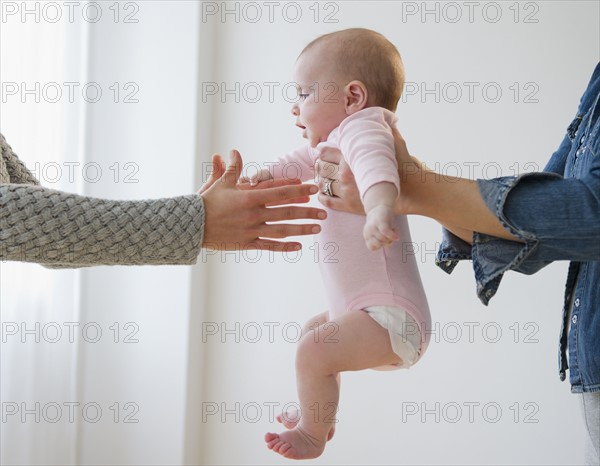 Two women holding baby boy (2-5 months) . Photo: Jamie Grill