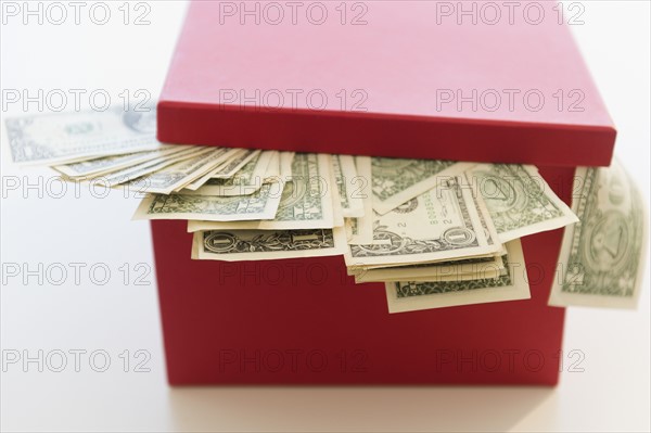 US dollar banknotes pouring out from box. Photo : Jamie Grill