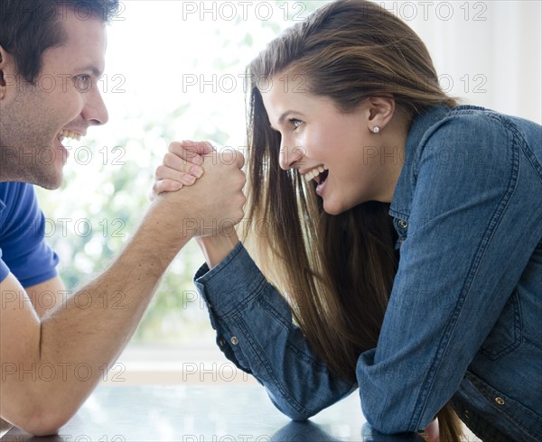 Happy young couple hand wrestling. Photo : Jamie Grill