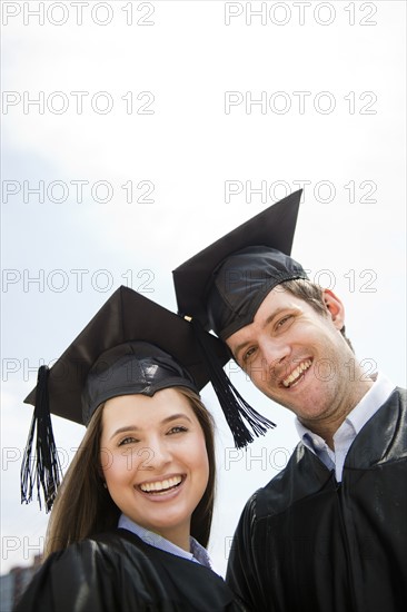 Young man and woman wearing graduation gowns. Photo : Jamie Grill