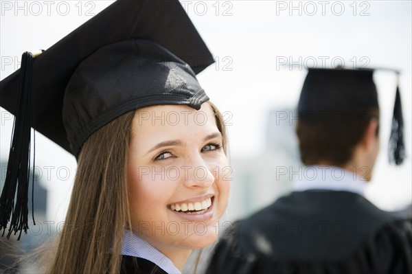 Young man and woman wearing graduation gowns. Photo : Jamie Grill