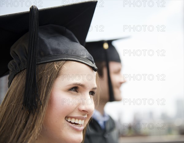 Profiles of young man and woman wearing graduation gowns. Photo : Jamie Grill