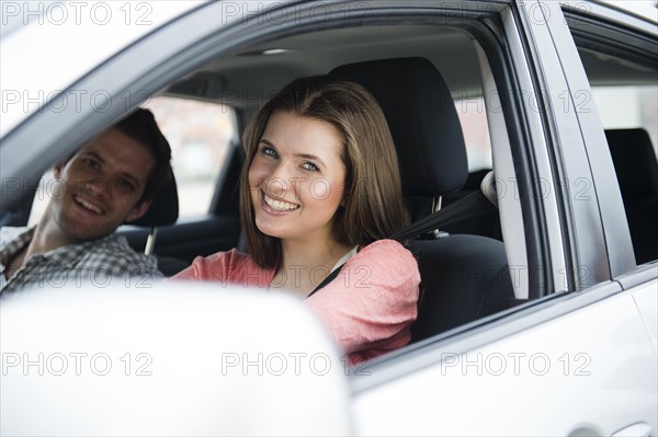 Happy young couple sitting in car. Photo : Jamie Grill