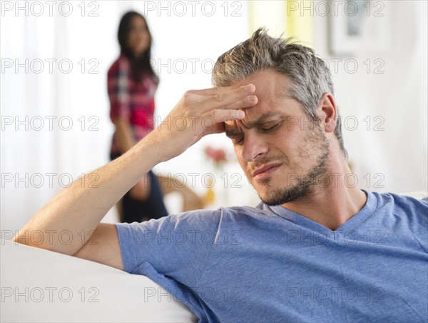 Man touching forehead, woman in background. Photo: Jamie Grill