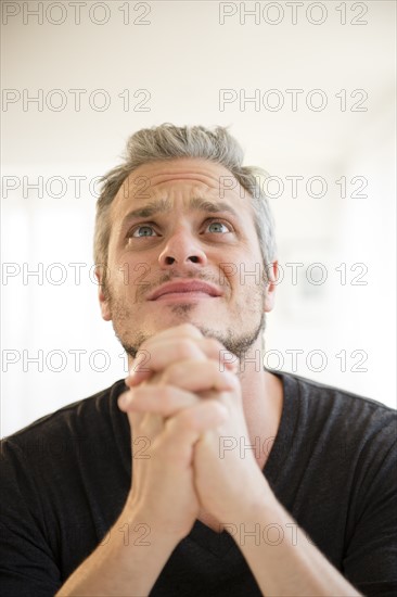 Mid adult man in praying gesture. Photo : Jamie Grill