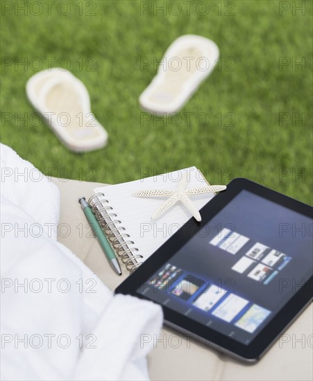 Digital tablet and notebook on lounger. Photo : Daniel Grill