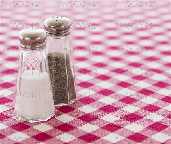 Salt and pepper shakers on checked tablecloth. Photo : Daniel Grill