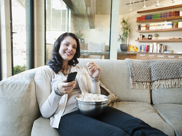 Woman sitting on couch with bowl of popcorn. Photo: Erik Isakson