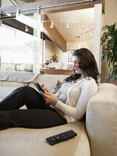 Woman using tablet while sitting on couch.