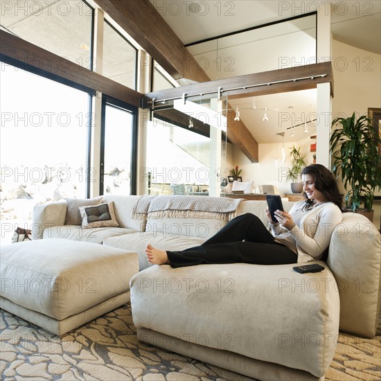 Woman using tablet while sitting on couch. Photo: Erik Isakson
