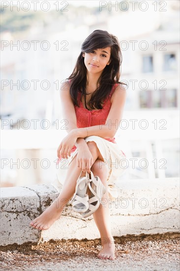 France, Cassis, Young woman sitting on stone wall. Photo : Mike Kemp