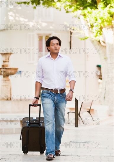 France, Cassis, Man walking with suitcase. Photo: Mike Kemp