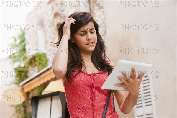 France, Cassis, Young woman using digital tablet on street. Photo : Mike Kemp