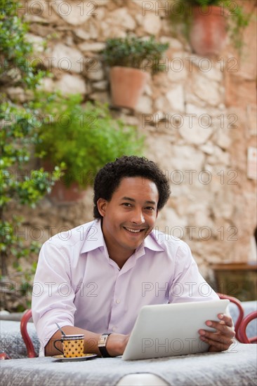 France, Cassis, Man using digital tablet in cafe. Photo : Mike Kemp