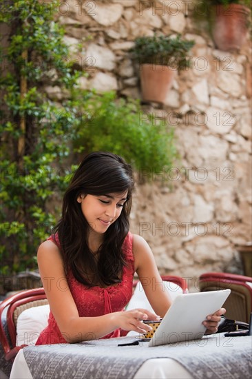 France, Cassis, Young woman using digital tablet in cafe. Photo : Mike Kemp