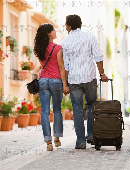 France, Cassis, Couple of tourist walking street with suitcase. Photo : Mike Kemp