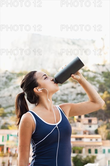 France, Marseille, Young woman in tracksuit drinking water. Photo: Mike Kemp