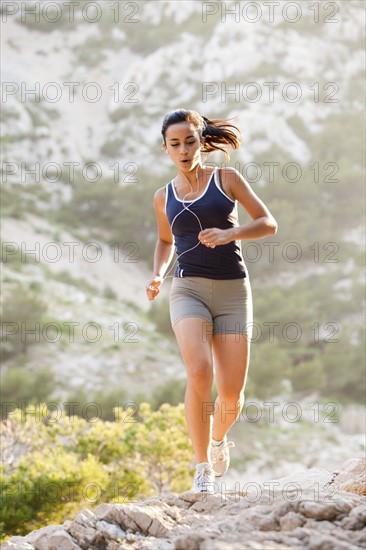 France, Marseille, Young woman jogging on rocky terrain. Photo : Mike Kemp