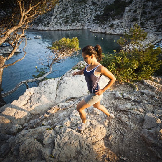 France, Marseille, Young woman jogging in rocky terrain. Photo : Mike Kemp