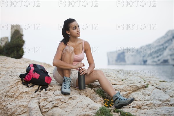 France, Marseille, Female hiker resting on rocky beach. Photo : Mike Kemp