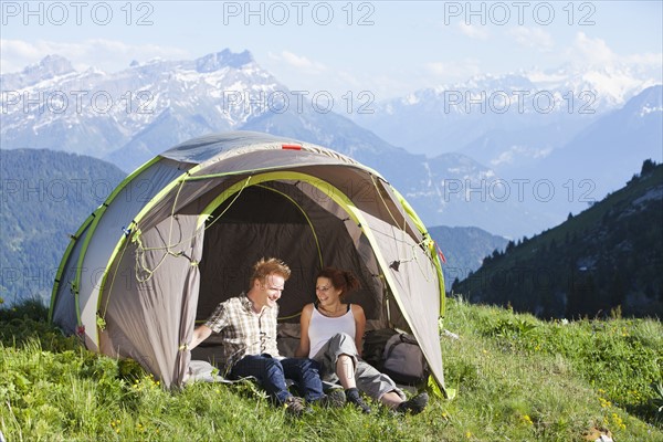 Switzerland, Leysin, Hikers resting in tent pitched on meadow. Photo: Mike Kemp