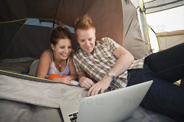 Hikers in tent using laptop. Photo : Mike Kemp