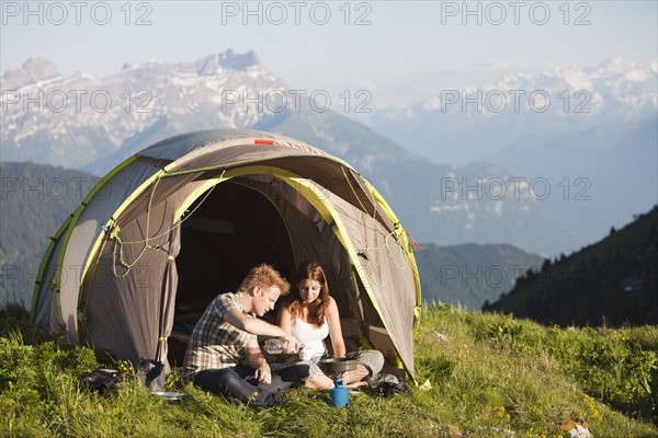 Switzerland, Leysin, Hikers preparing breakfast on Alpine meadow. Photo : Mike Kemp