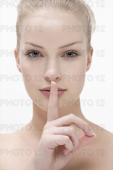 Young woman pressing finger against mouth. Photo : Jan Scherders