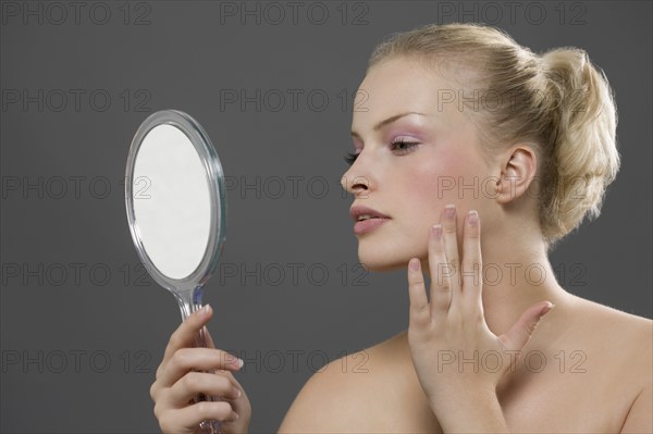 Beauty portrait of woman looking in mirror. Photo : Jan Scherders