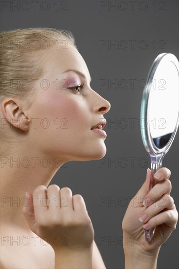 Beauty portrait of woman looking in mirror. Photo : Jan Scherders
