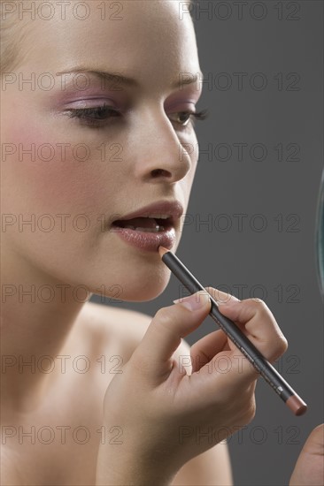 Beauty portrait of woman using lip liner. Photo : Jan Scherders