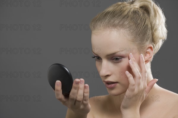 Beauty portrait of woman using powder compact. Photo: Jan Scherders