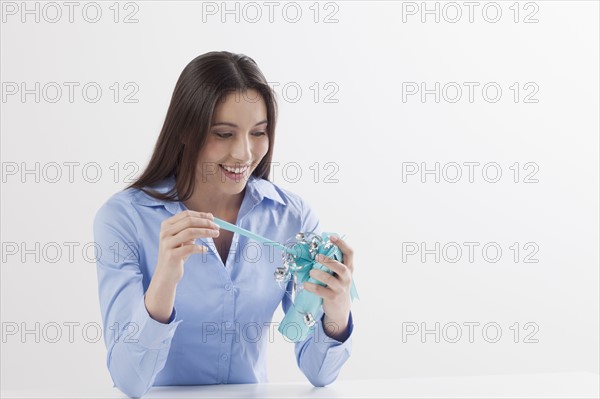 Studio shot of woman opening present. Photo : Jan Scherders