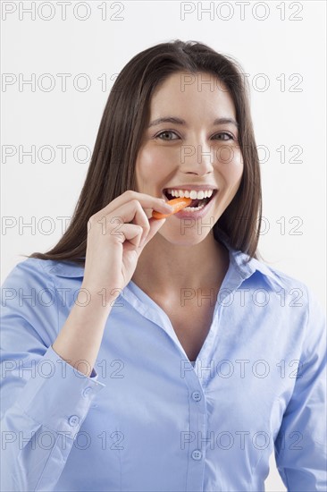Studio shot of woman eating baby carrots. Photo: Jan Scherders