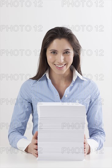 Studio shot of woman with stack of documents. Photo : Jan Scherders