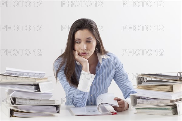 Studio shot of woman with stack of documents. Photo: Jan Scherders