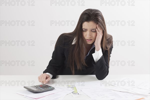 Studio shot of businesswoman with calculator and bills. Photo : Jan Scherders