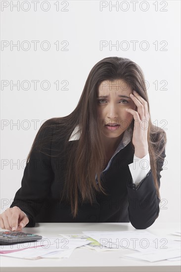 Studio shot of businesswoman with calculator and bills. Photo : Jan Scherders