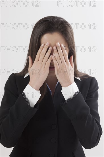 Portrait of young woman with hands covering eyes, studio shot. Photo : Jan Scherders