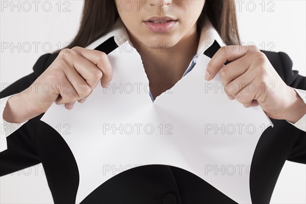 Young businesswoman tearing paper, close-up. Photo : Jan Scherders
