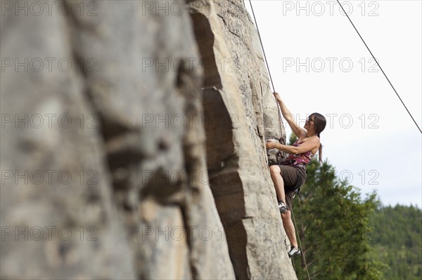 Smiling woman rock climbing. Photo: Noah Clayton