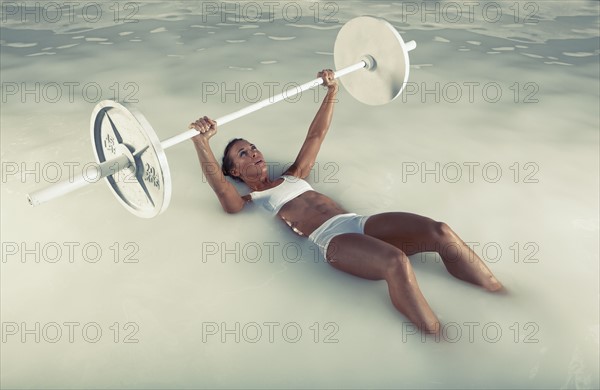 Young woman weight lifting in water. Photo : King Lawrence