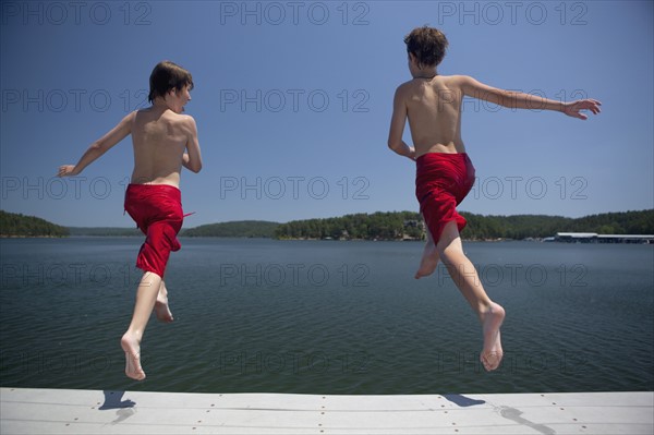 USA, Arkansas, Murfreesboro, Two brothers (8-9, 12-13) jumping into water. Photo: King Lawrence