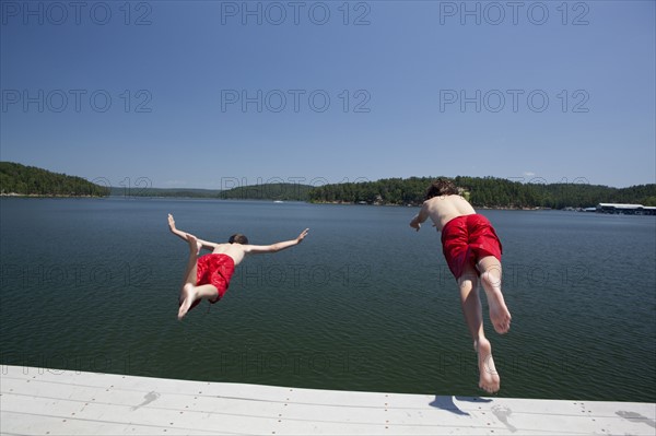 USA, Arkansas, Murfreesboro, Two brothers (8-9, 12-13) jumping into water. Photo: King Lawrence