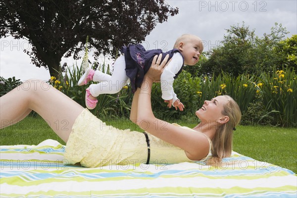 Young mother playing with daughter outdoor. Photo : Mark de Leeuw